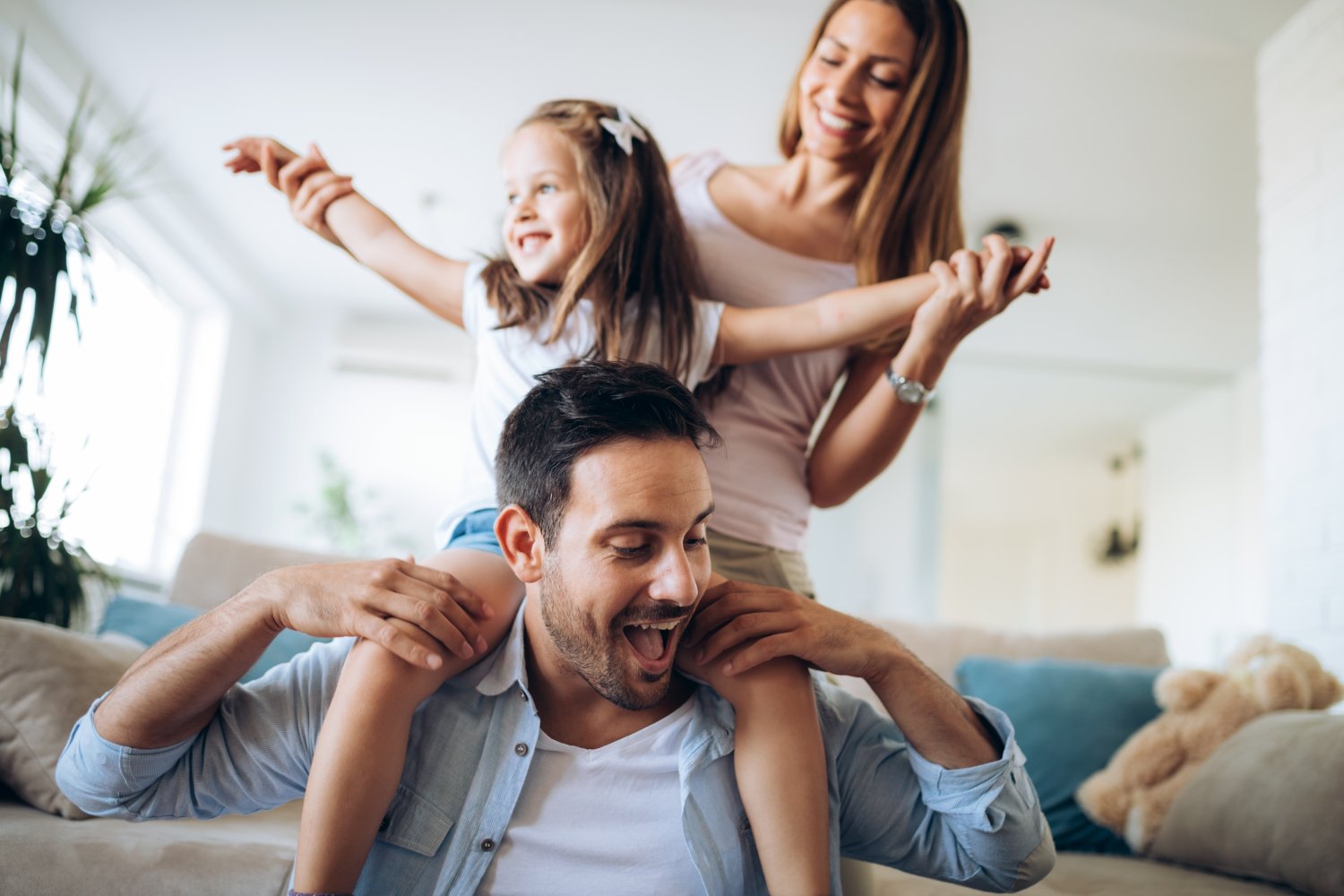 homepage-hero-image Mom and Dad playing with their daughter on the Dads shoulders